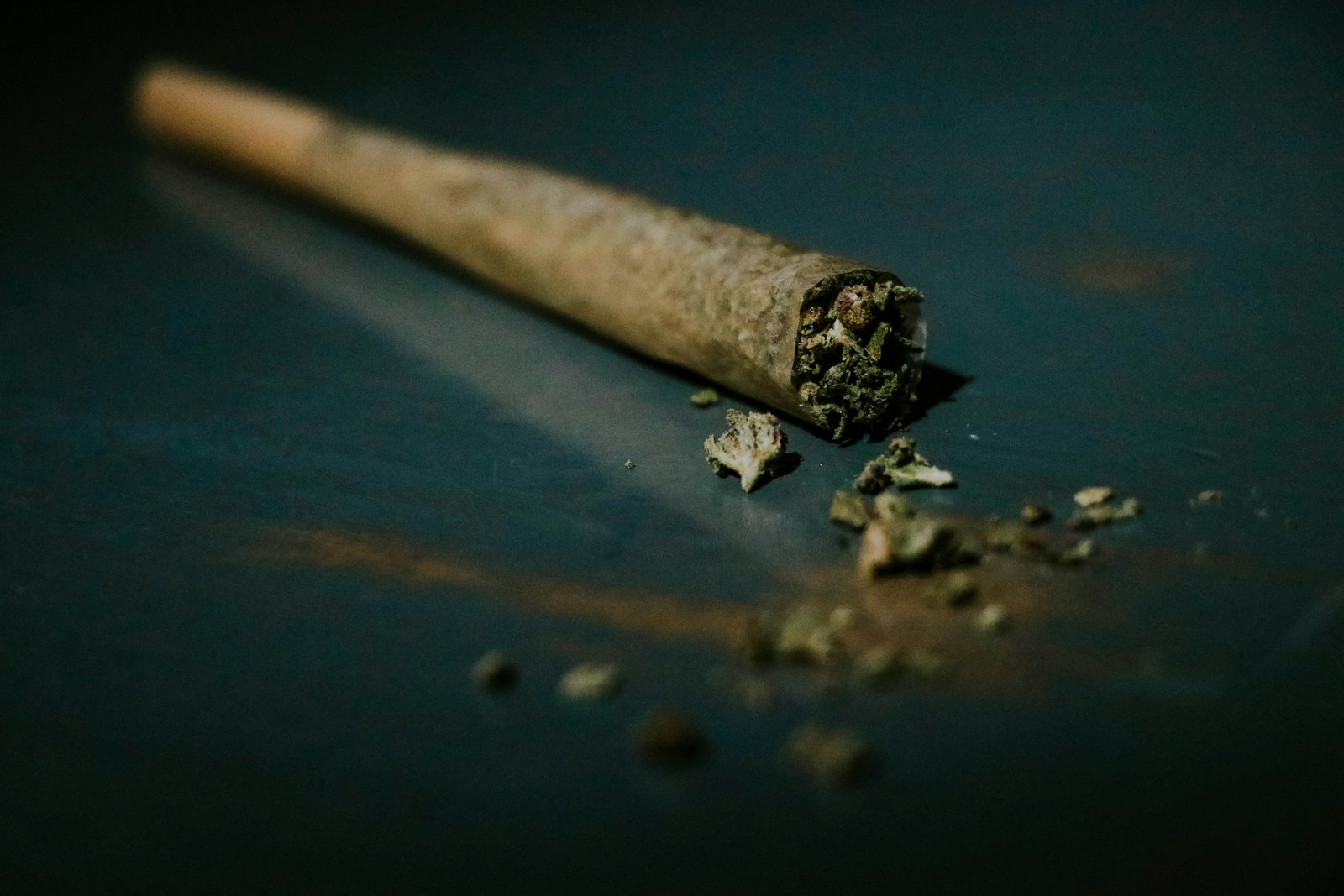 A rolled cannabis joint on a blue surface